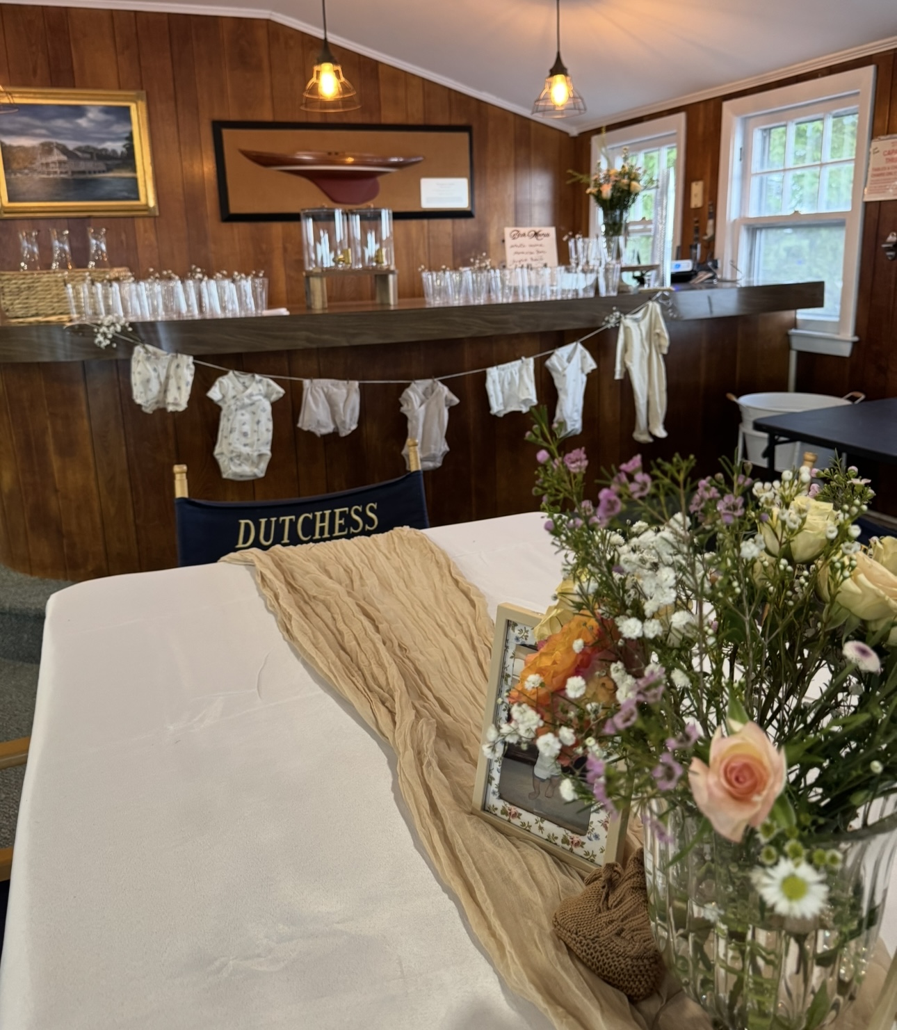 Baby shower setup with onesie banner and floral centerpiece