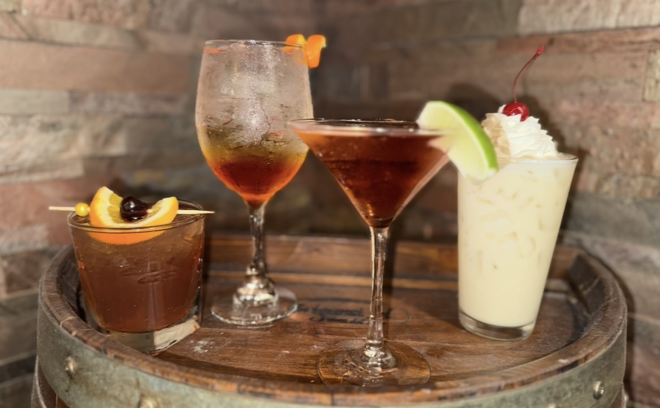 Four signature cocktails styled on a whiskey barrel
