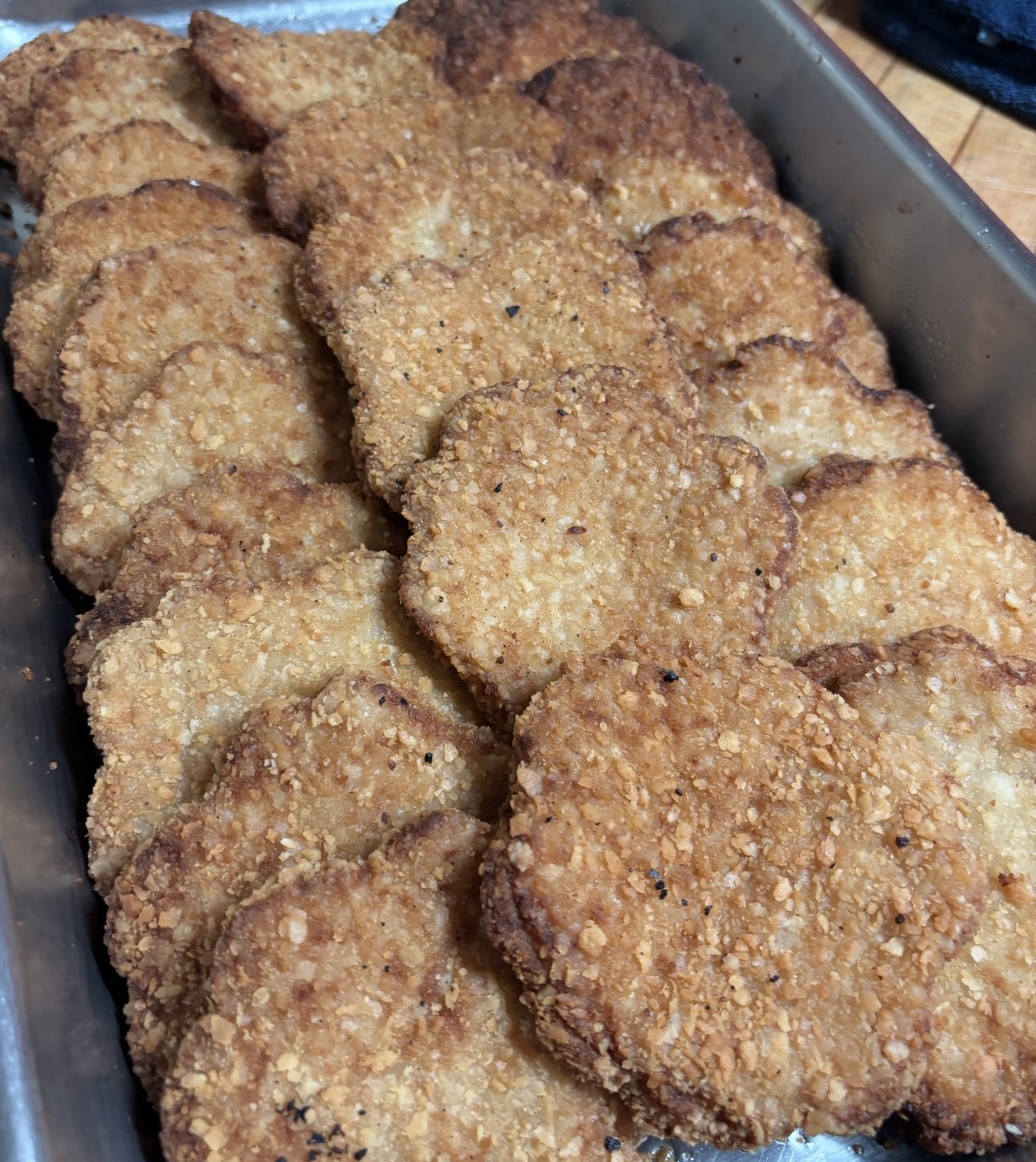 Golden breaded chicken cutlets arranged in a serving pan