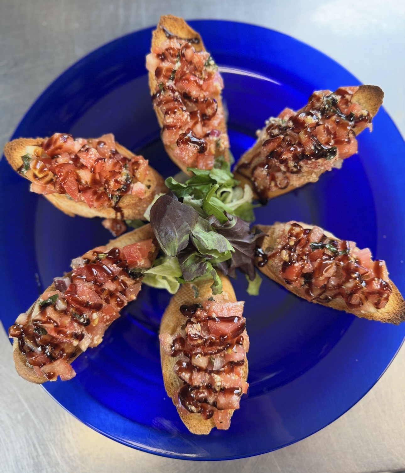 Tomato bruschetta with balsamic glaze on a cobalt plate