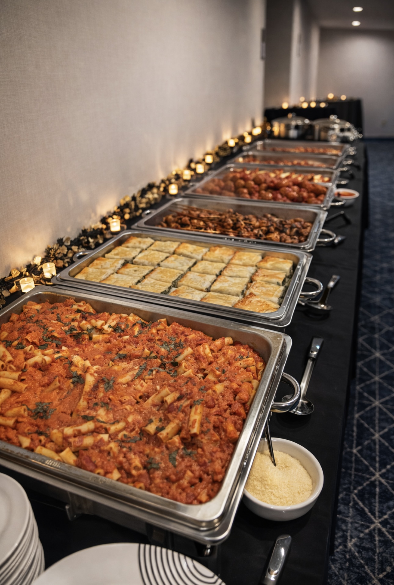 Long Italian buffet line with penne vodka, spinach pie, meatballs, and chicken skewers