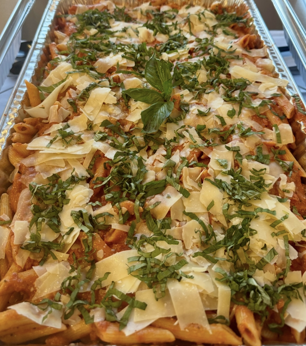 Penne alla vodka catering tray topped with basil and parmesan