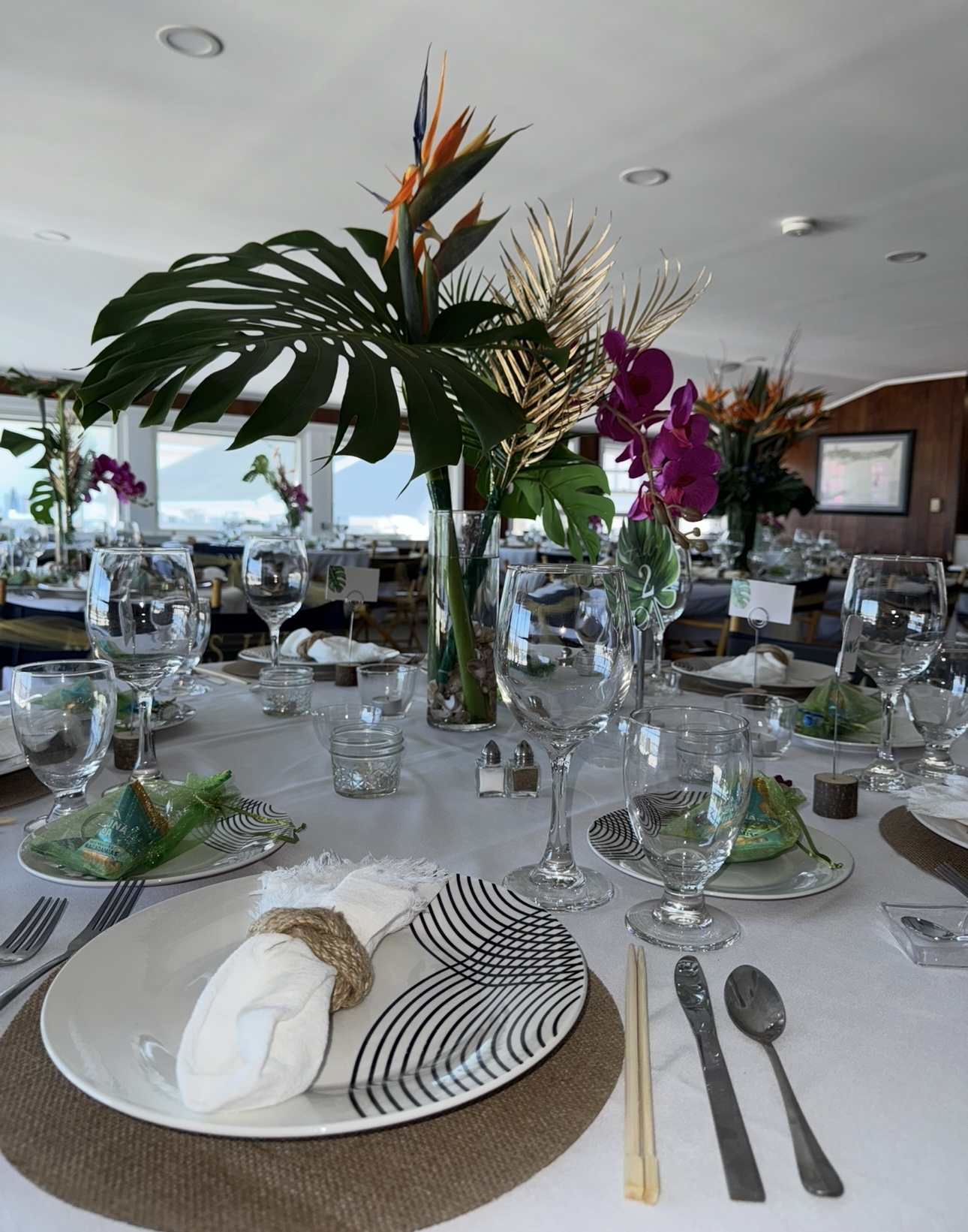 Tropical place setting with monstera, orchids, and bird of paradise