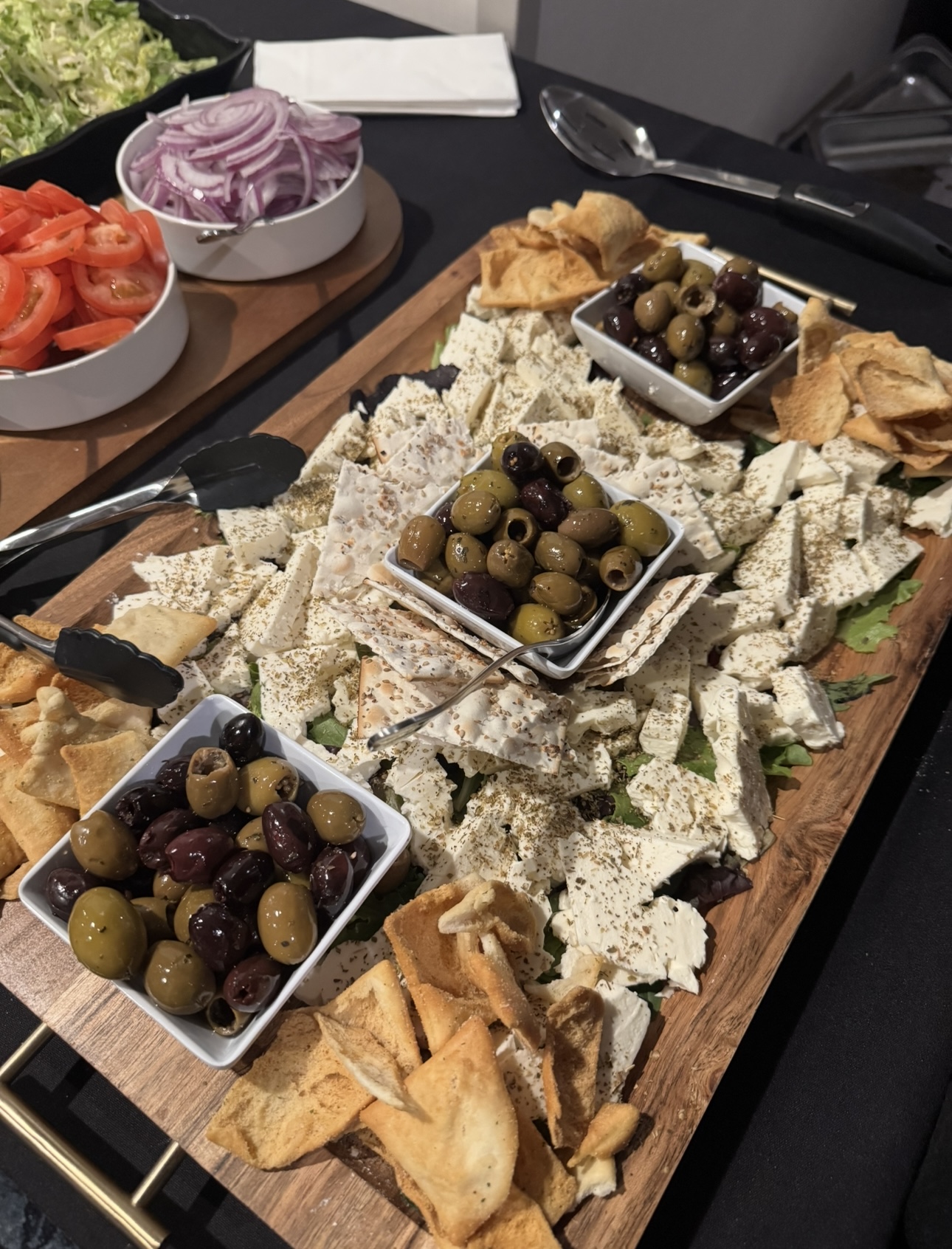 Mediterranean board with feta, mixed olives, pita chips, tomatoes, and red onion