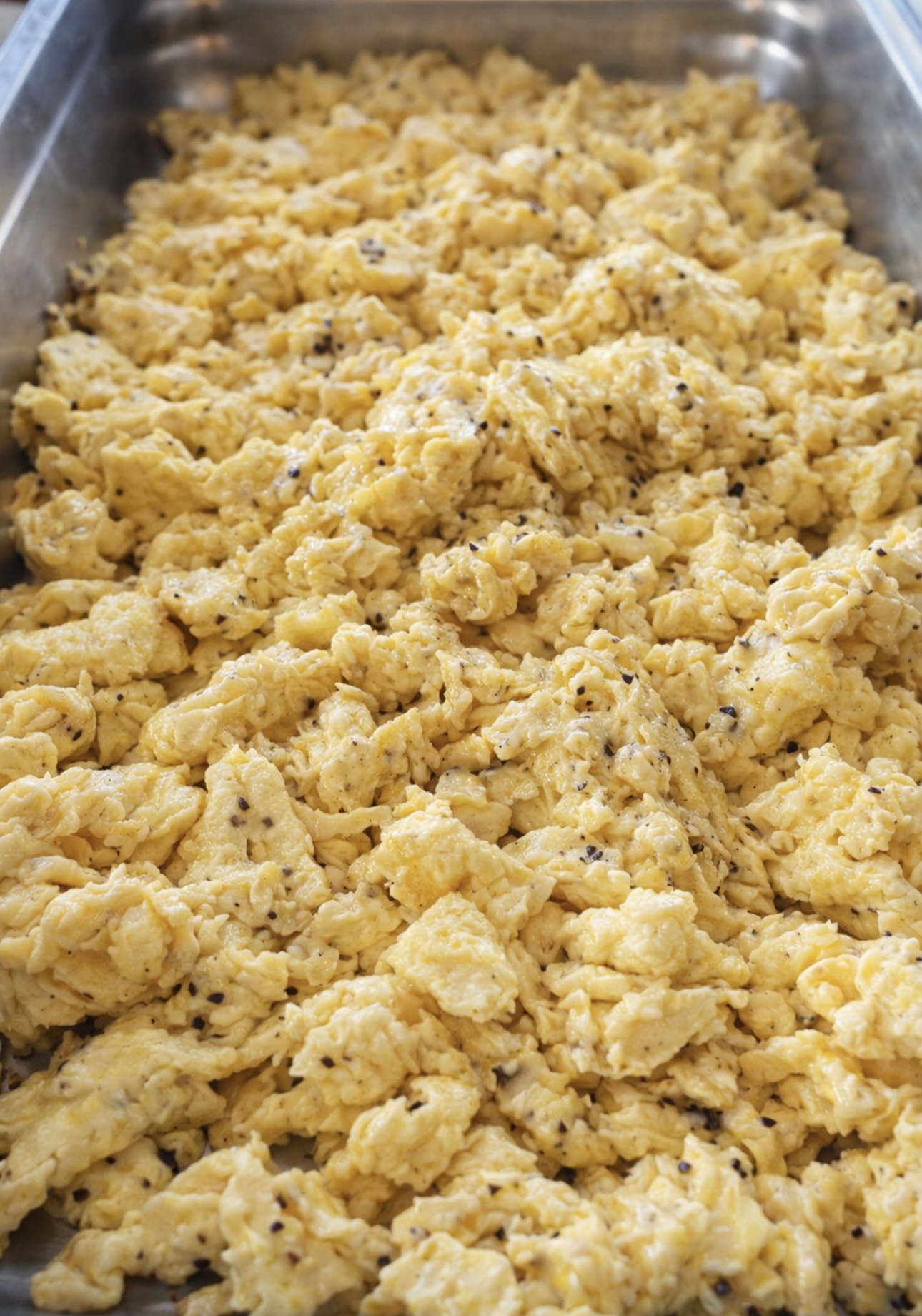 Tray of fluffy scrambled eggs with cracked black pepper