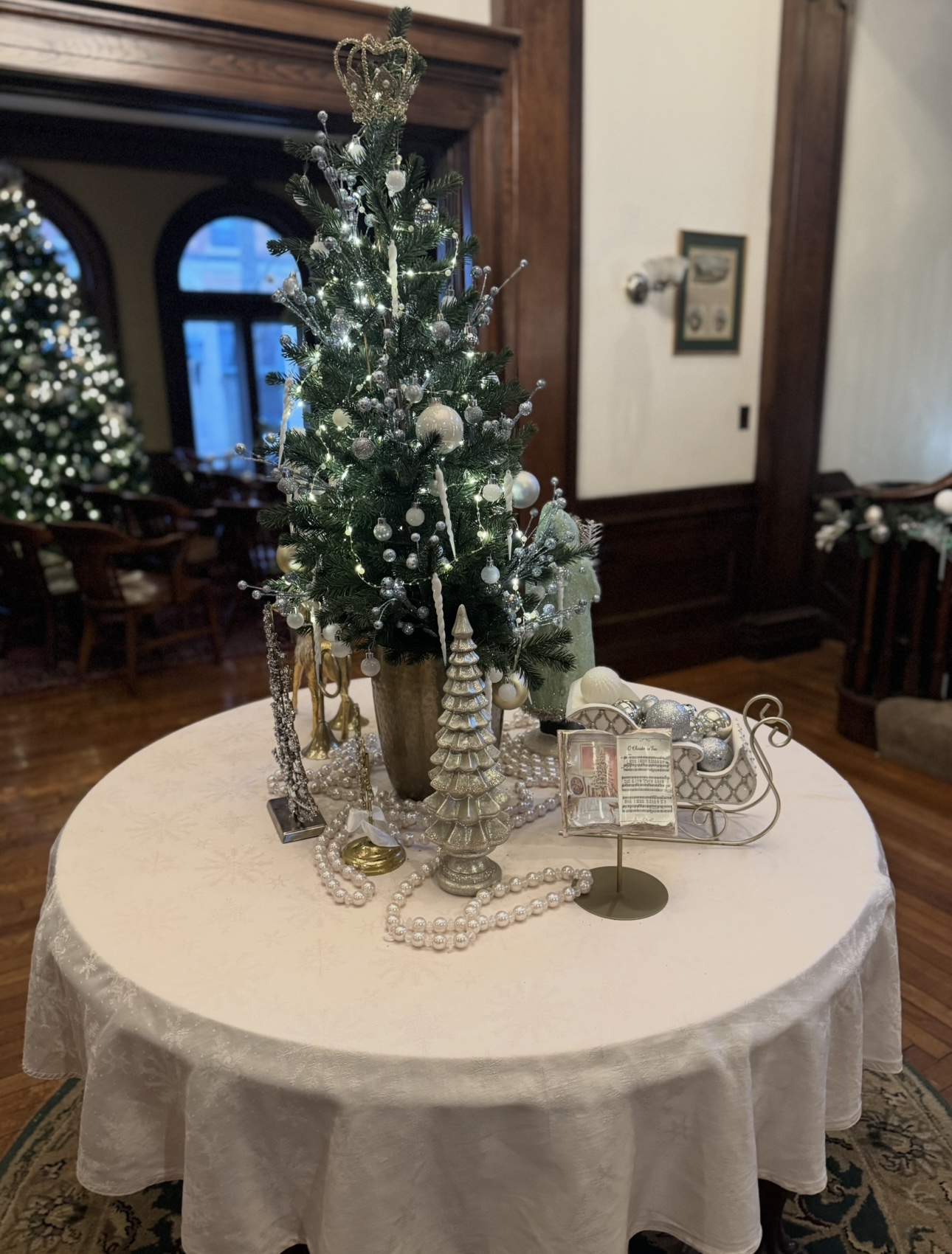 Christmas centerpiece display with lit tabletop tree and silver decor