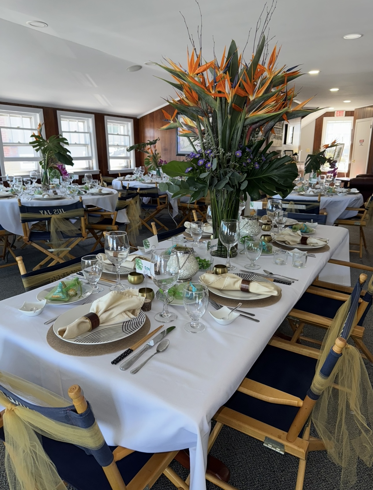 Event room with bird of paradise centerpiece and tropical place settings